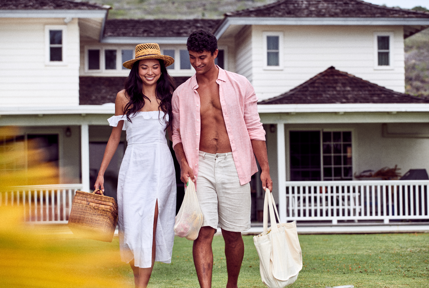 This image shows a man and a woman walking outside next to a house, carrying reusable cotton tote and grocery produce bags. These are a part of Desesh's range of zero waste, plastic free, eco friendly, more sustainable personal care and everyday essential products.