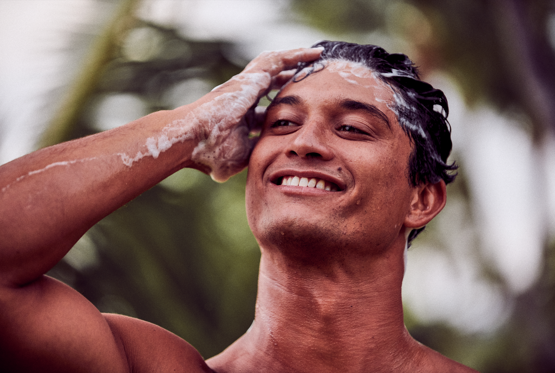 This image shows salon quality Argan Oil Shampoo bars with plastic free biodegradable packaging for a more sustainable eco friendly zero waste hair care routine. In the image the man is lathering his hair and creating a lot of suds.