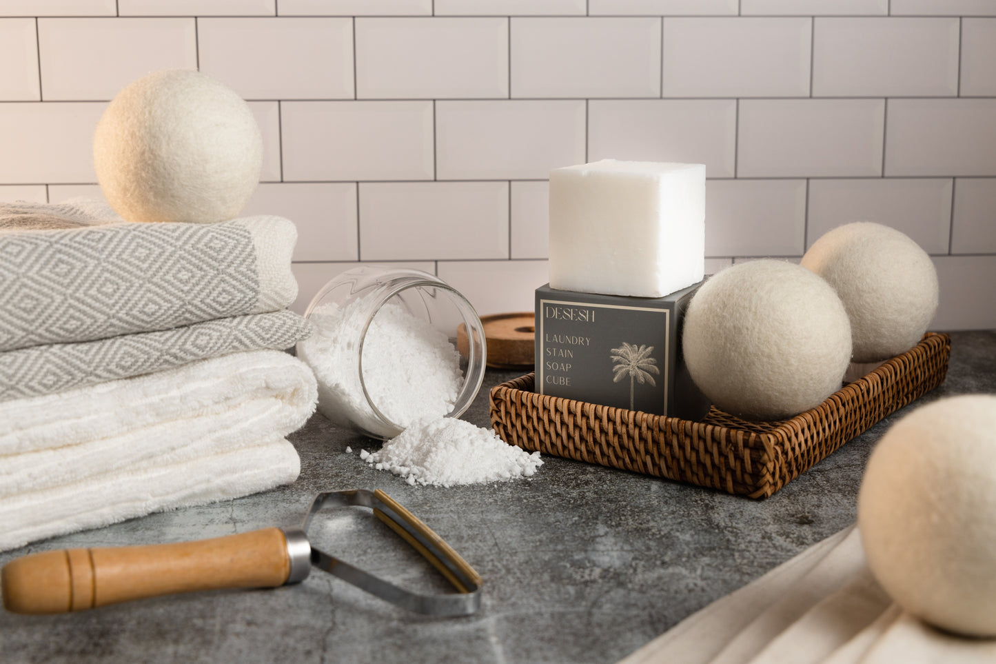 This image shows a reusable bamboo and metal lint remover as an alternative to single use disposable plastic lint rollers. This is designed for a plastic free zero waste more sustainable eco friendly routine and lifestyle. Also shown in the image are other plastic free laundry products offered by Desesh