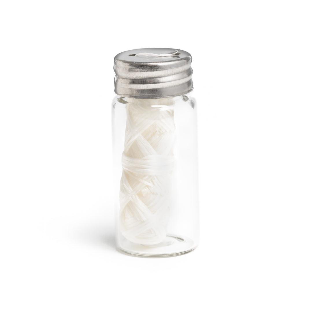 This image shows a glass jar with metal lid containing biodegradable plant-based dental floss for a more sustainable eco friendly plastic free dental and oral hygiene routine