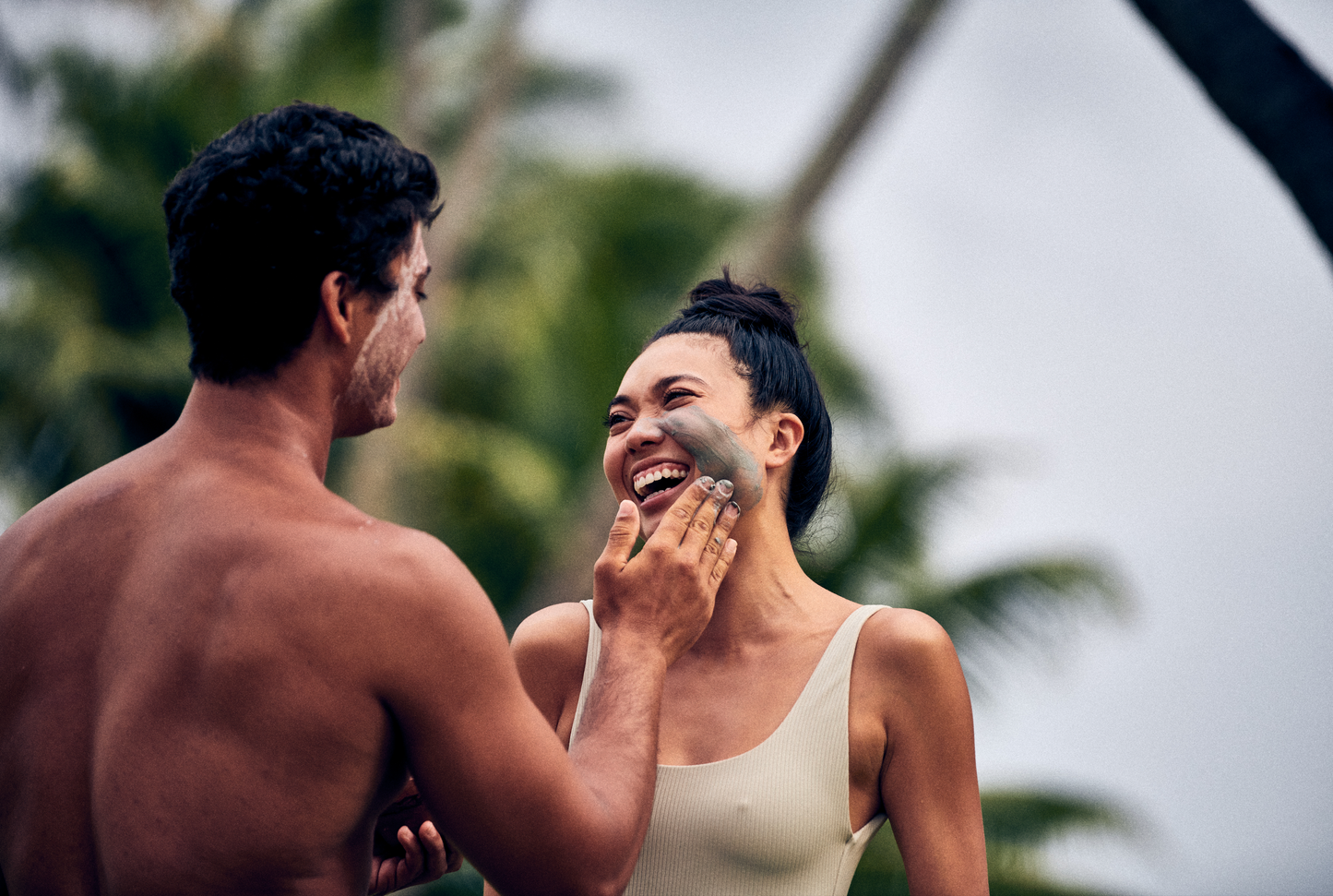 This image shows the Desesh US-made spa quality mineral face mask powder as an alternative to single use face mask sheets for a more environmentally friendly zero waste plastic free self care face mask routine. In the image a man is applying the charcoal mineral face mask powder to a woman while smiling