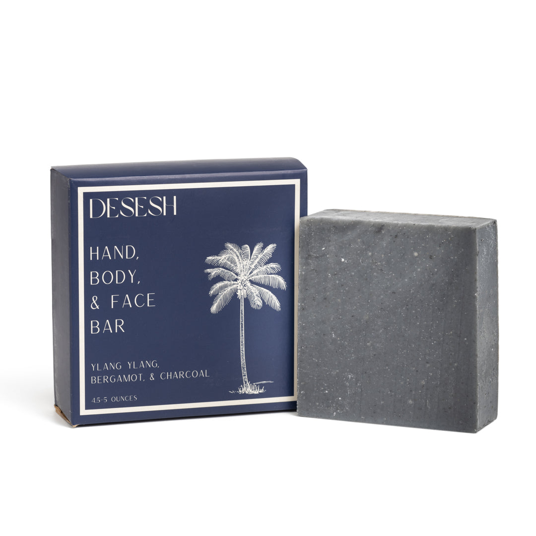 This photo shows the Desesh premium quality US-made small batch body hand and face soap bar with plastic free biodegradable packaging. In the image is the Ylang Ylang Bergamot and Charcoal soap bar