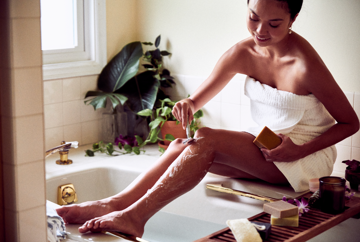 This image shows a metal reusable safety razor for body and face shaving as a plastic free alternative to disposable razors. It comes with replacement blades. It is designed for eco friendly zero waste plastic free more sustainable shaving. In the image a woman is using the metal safety razor to shave her legs